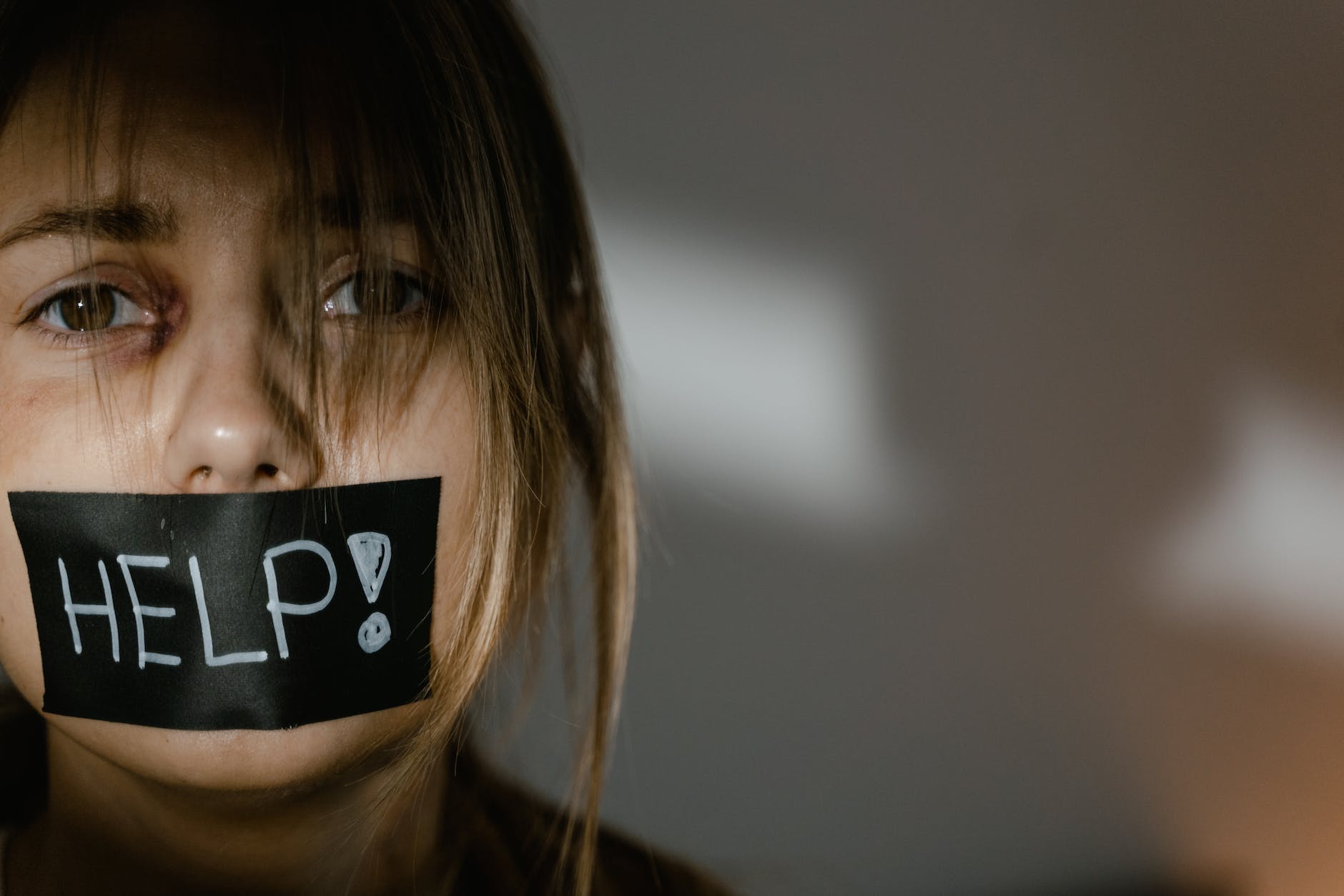 Visage de femme triste avec la bouche occultée par le message "Help"
